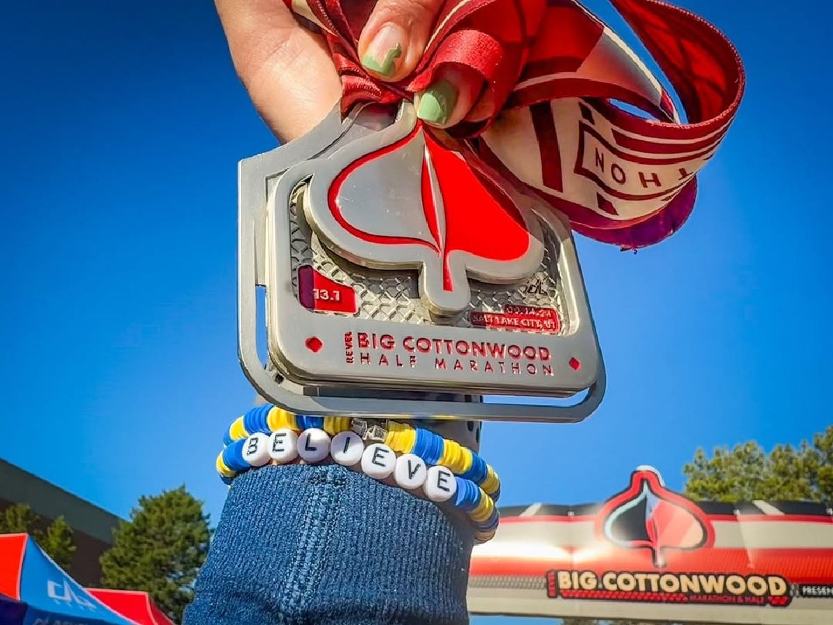 participant holding up the medal for finishing the big cottonwood half marathon