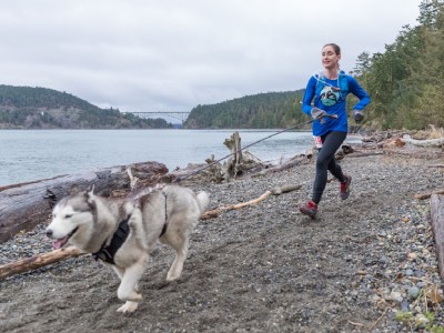 woman and husky running on the deception pass coastline